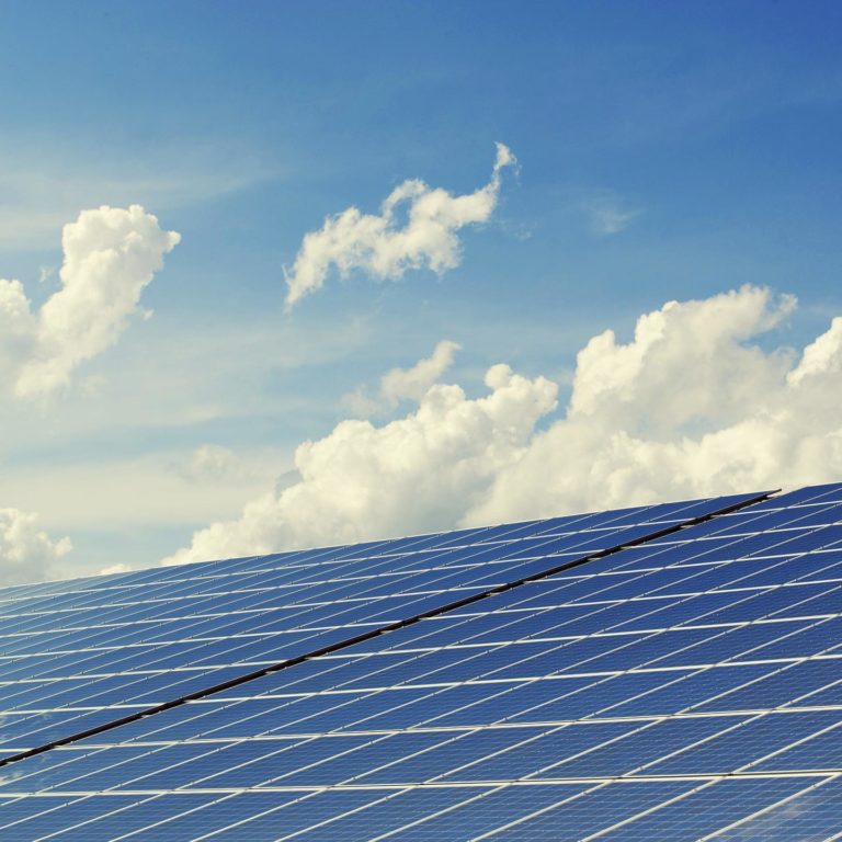 Solar panels on a building against blue sky with clouds