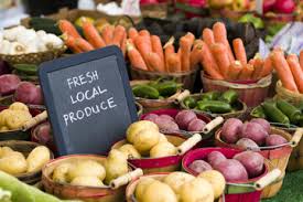 Colorful vegetables on a market stand with a chalkboard sign that reads "Fresh Local Produce"